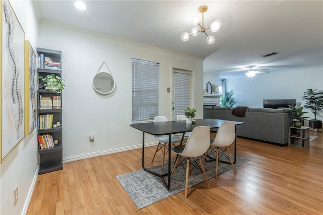 dining space featuring crown molding, baseboards, visible vents, and light wood-style floors