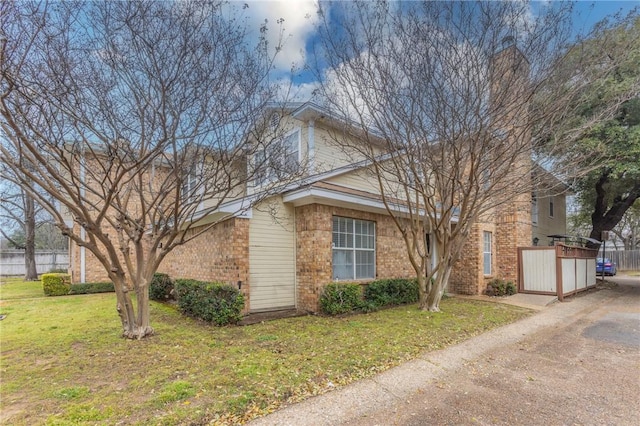 exterior space with fence, a lawn, and brick siding