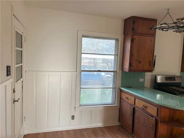 kitchen with tasteful backsplash, a healthy amount of sunlight, tile countertops, and light hardwood / wood-style floors