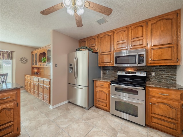 kitchen featuring backsplash, stainless steel appliances, and dark stone counters