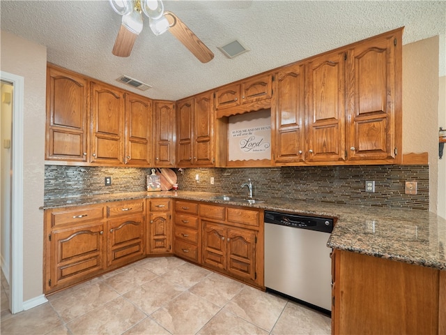 kitchen with dark stone counters, dishwasher, sink, and backsplash