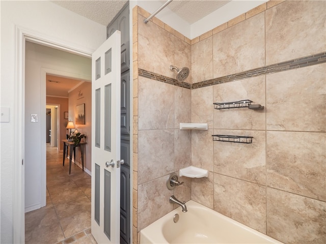 bathroom featuring a textured ceiling and tiled shower / bath