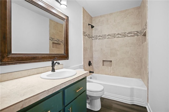 full bathroom featuring wood-type flooring, toilet, tiled shower / bath combo, and vanity