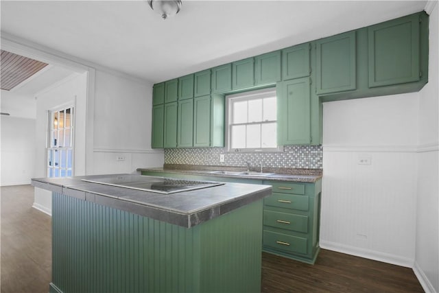 kitchen featuring dark hardwood / wood-style floors, tasteful backsplash, sink, green cabinets, and black electric cooktop