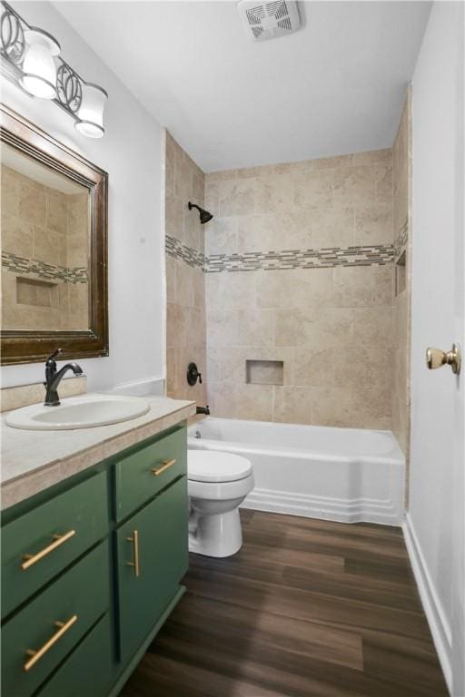 full bathroom featuring vanity, tiled shower / bath combo, wood-type flooring, and toilet