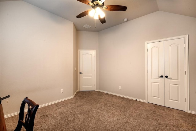 unfurnished bedroom with ceiling fan, a closet, lofted ceiling, and dark colored carpet