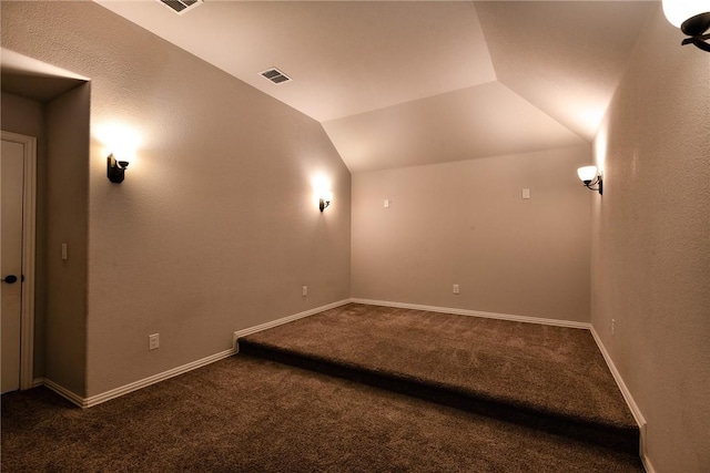 cinema room featuring vaulted ceiling and dark carpet