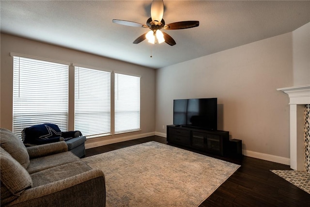 living room featuring ceiling fan, dark hardwood / wood-style flooring, and a fireplace