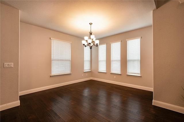 empty room featuring dark wood-type flooring and a chandelier