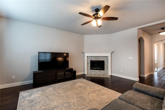 living room featuring ceiling fan, dark hardwood / wood-style floors, and a tile fireplace