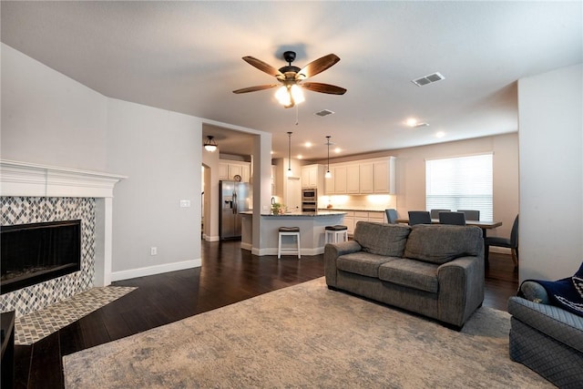 living room with ceiling fan, dark hardwood / wood-style floors, and a fireplace