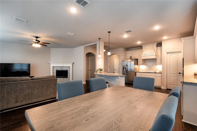 dining room with ceiling fan, sink, dark hardwood / wood-style flooring, and a fireplace