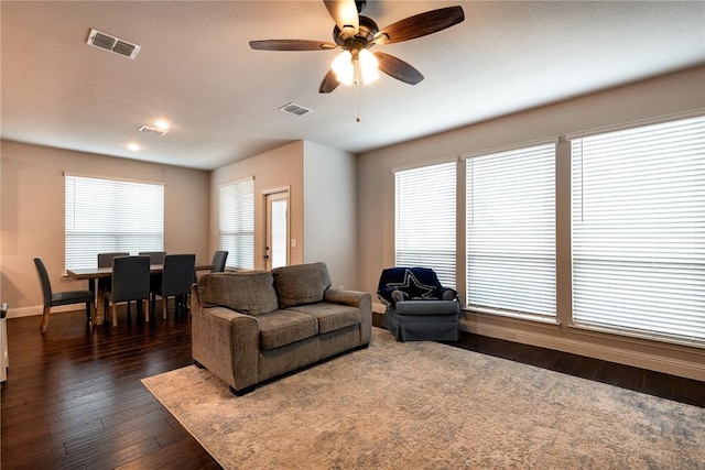 living room featuring dark wood-type flooring and ceiling fan