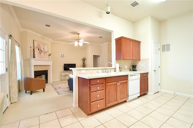 kitchen with white dishwasher, sink, ornamental molding, a fireplace, and light tile patterned flooring