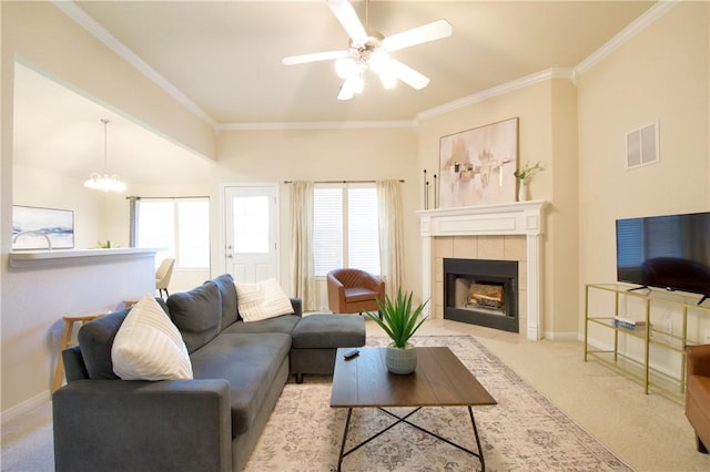 carpeted living room featuring a tile fireplace, ceiling fan with notable chandelier, and crown molding