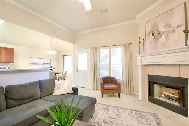 living room with crown molding, a fireplace, light colored carpet, and ceiling fan with notable chandelier