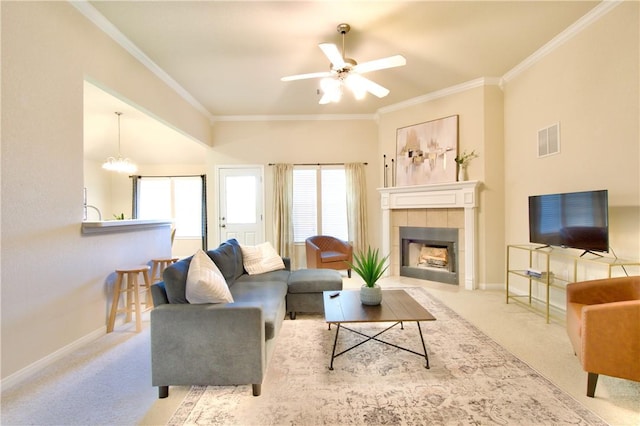 carpeted living room featuring a fireplace, ceiling fan with notable chandelier, and ornamental molding