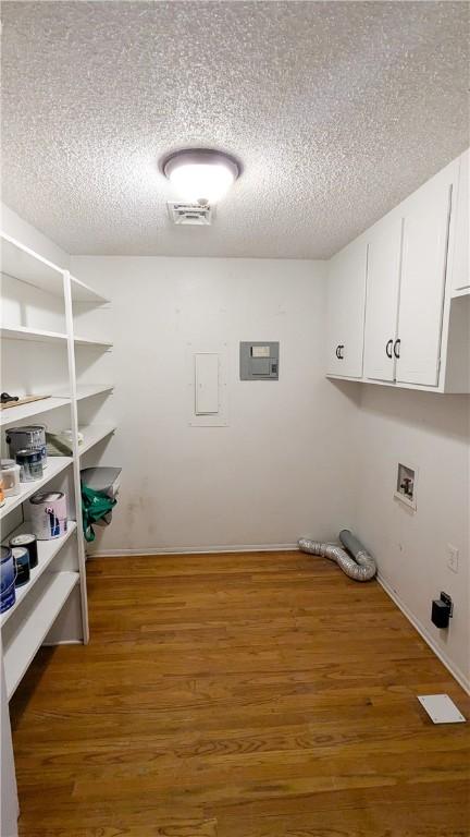 laundry area featuring a textured ceiling, washer hookup, wood finished floors, visible vents, and cabinet space