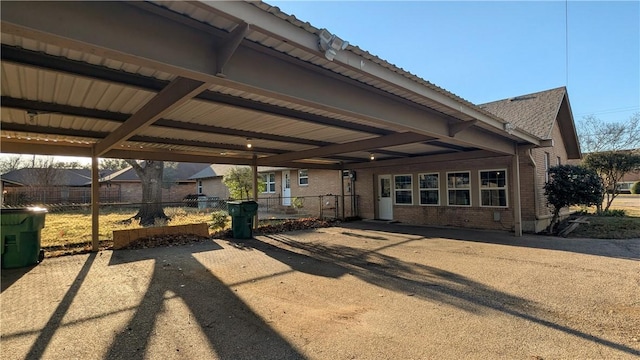 exterior space featuring brick siding, fence, and driveway