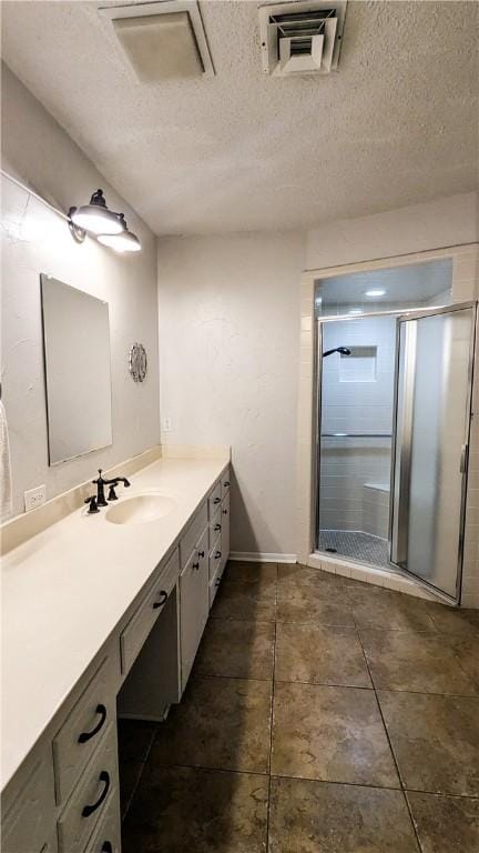 bathroom with a shower stall, visible vents, a textured ceiling, and vanity