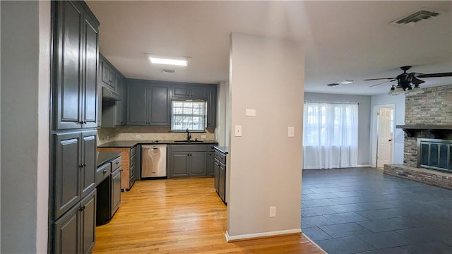 kitchen featuring dark countertops, visible vents, open floor plan, a brick fireplace, and a sink