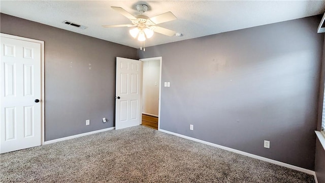 unfurnished bedroom with carpet floors, visible vents, baseboards, and a ceiling fan