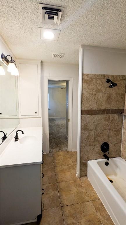 full bathroom with visible vents, a textured ceiling, vanity, and bathing tub / shower combination