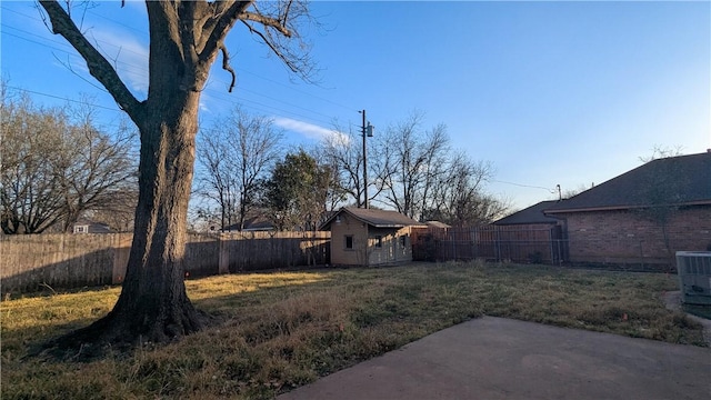 view of yard featuring a fenced backyard, central AC, and an outdoor structure