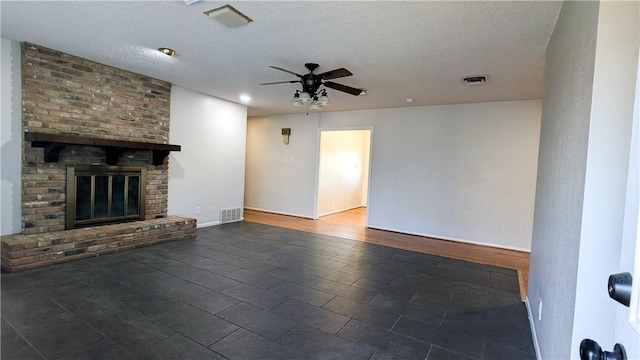 unfurnished living room featuring ceiling fan, a fireplace, visible vents, and a textured ceiling