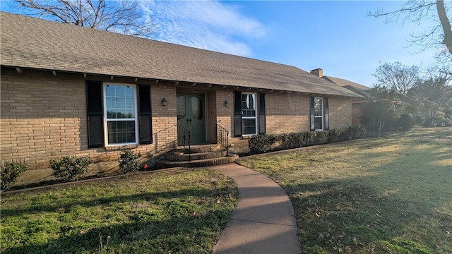 ranch-style house with brick siding, roof with shingles, and a front yard