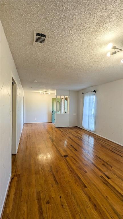 spare room with visible vents, a textured ceiling, and hardwood / wood-style flooring