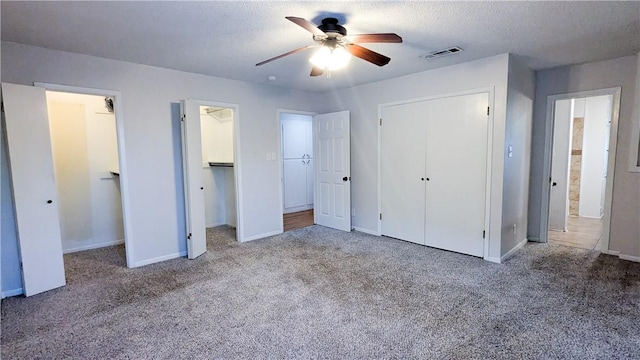 unfurnished bedroom featuring a textured ceiling, carpet, visible vents, and baseboards