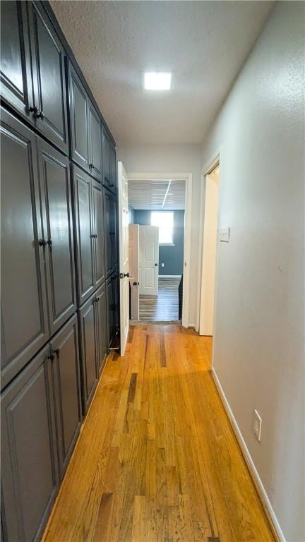 hall featuring light wood-style flooring and baseboards