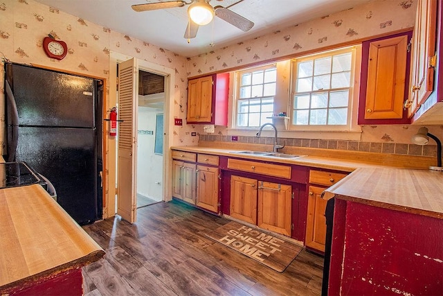 kitchen featuring black fridge, sink, ceiling fan, dark hardwood / wood-style flooring, and butcher block counters