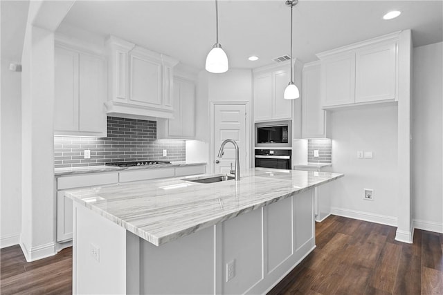 kitchen featuring white cabinets, oven, a center island with sink, sink, and built in microwave