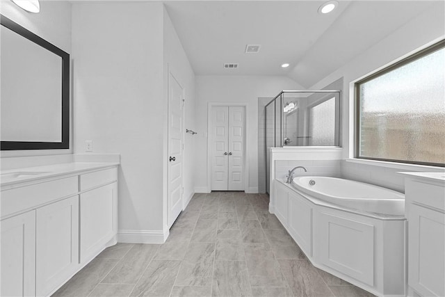 bathroom featuring vanity, independent shower and bath, and vaulted ceiling