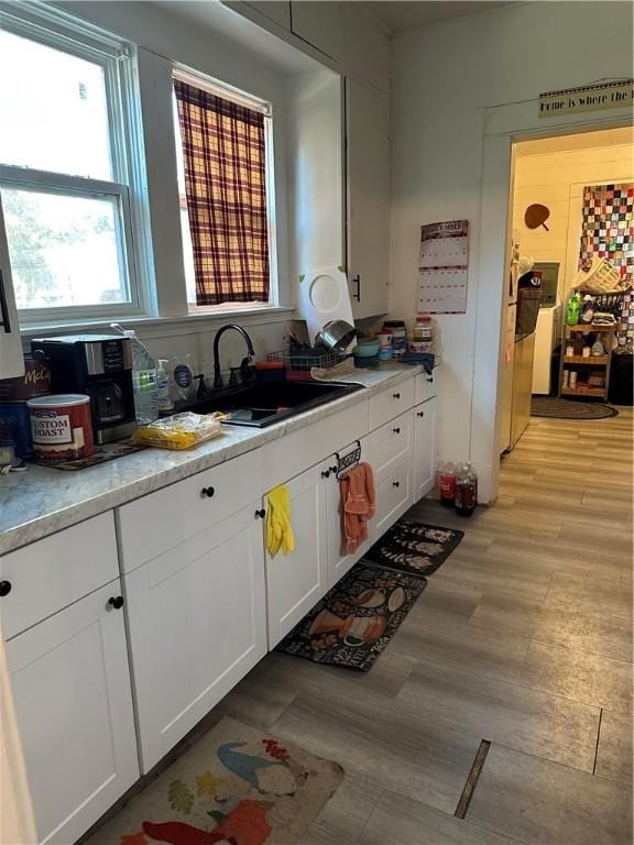 kitchen featuring white cabinets, light hardwood / wood-style floors, and sink