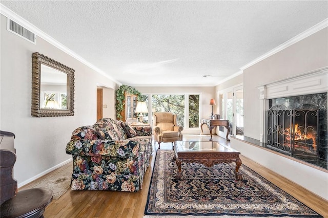 living room with crown molding, a premium fireplace, a textured ceiling, and light hardwood / wood-style flooring