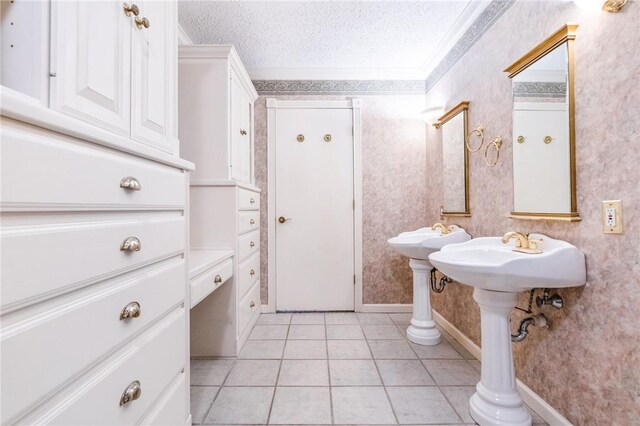 bathroom with tile patterned floors, crown molding, dual sinks, and a textured ceiling