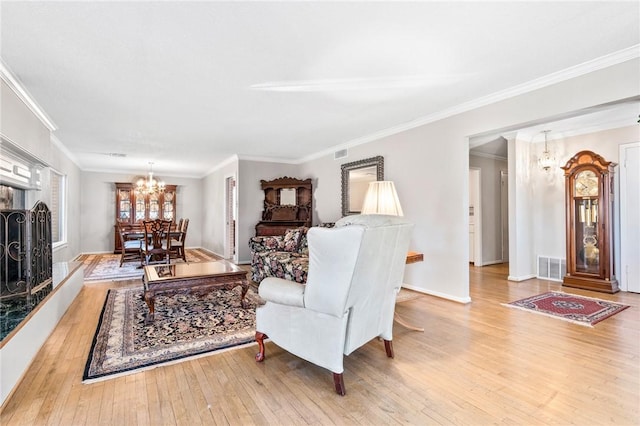 living room with ornamental molding, light wood-type flooring, and a notable chandelier