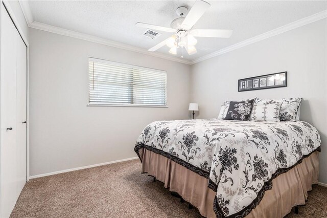 carpeted bedroom with ceiling fan, a closet, and ornamental molding