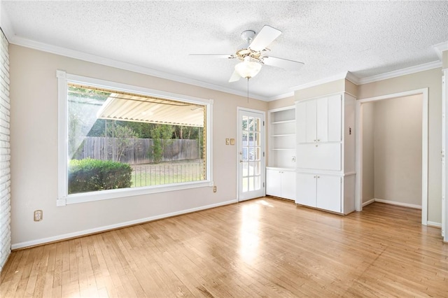 spare room featuring a textured ceiling, light wood-type flooring, and crown molding