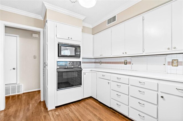 kitchen featuring backsplash, white cabinets, black appliances, and light hardwood / wood-style floors