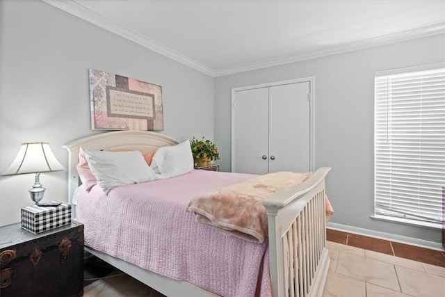 tiled bedroom featuring a closet, baseboards, and crown molding