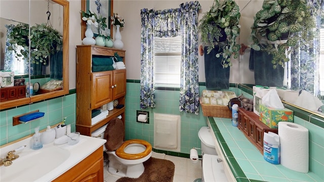 bathroom with tile patterned floors, vanity, toilet, and tile walls