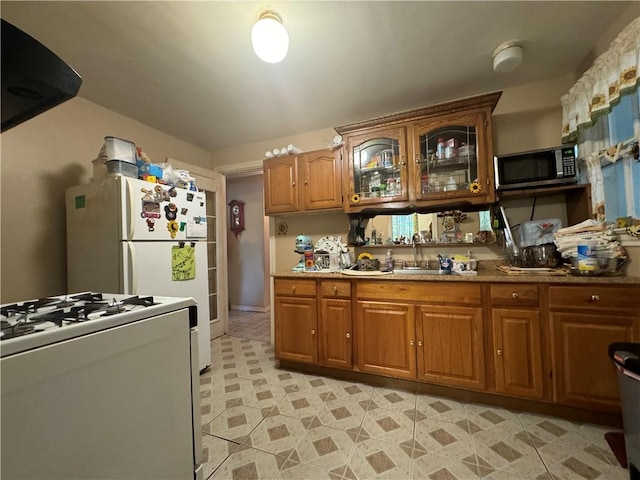 kitchen featuring range hood, white appliances, and sink