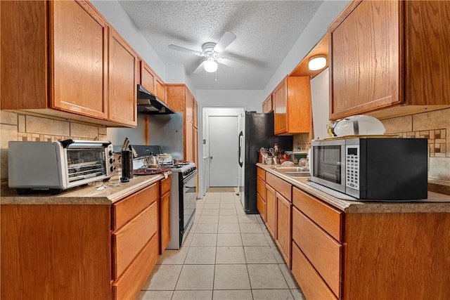 kitchen featuring decorative backsplash, appliances with stainless steel finishes, a textured ceiling, ceiling fan, and light tile patterned floors