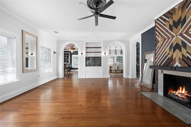 unfurnished living room with plenty of natural light, dark hardwood / wood-style floors, and ornamental molding