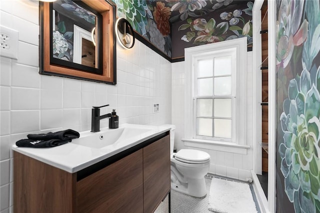 bathroom featuring tile patterned flooring, vanity, toilet, and tile walls