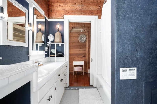 bathroom featuring wooden walls, shower / bath combo with shower curtain, vanity, and hardwood / wood-style floors